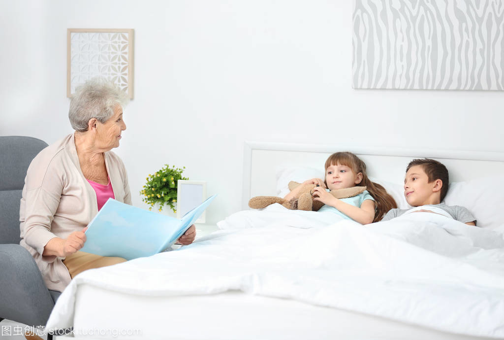 Senior nanny reading book to little boy indoors Senior nanny reading book to little boy indoors